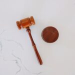 A wooden gavel and sound block are placed on a white marble surface.