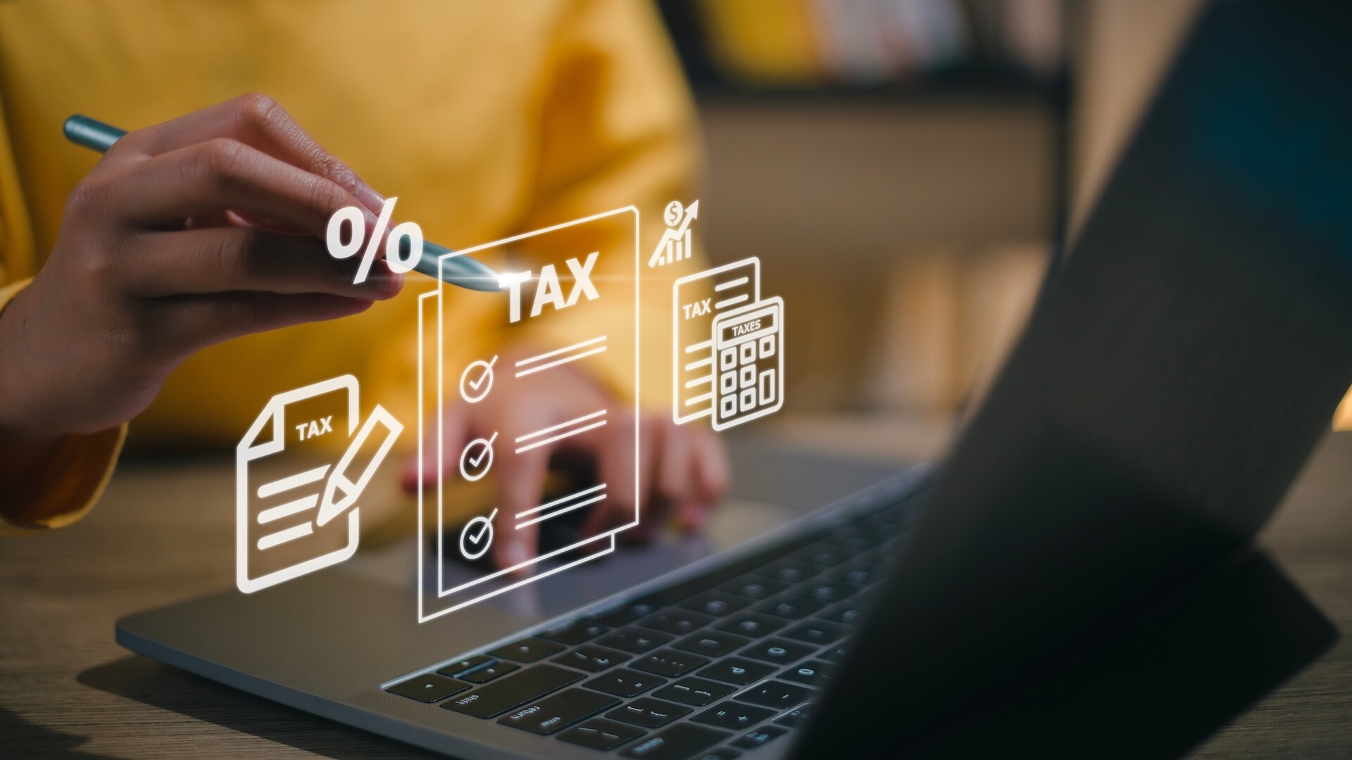A person uses a laptop with a stylus, surrounded by holographic tax-related icons like a checklist, percentage symbol, and calculator, highlighting efficient financial management and tax filing. Stay ahead of tax changes in 2025 with cutting-edge tools and insights.